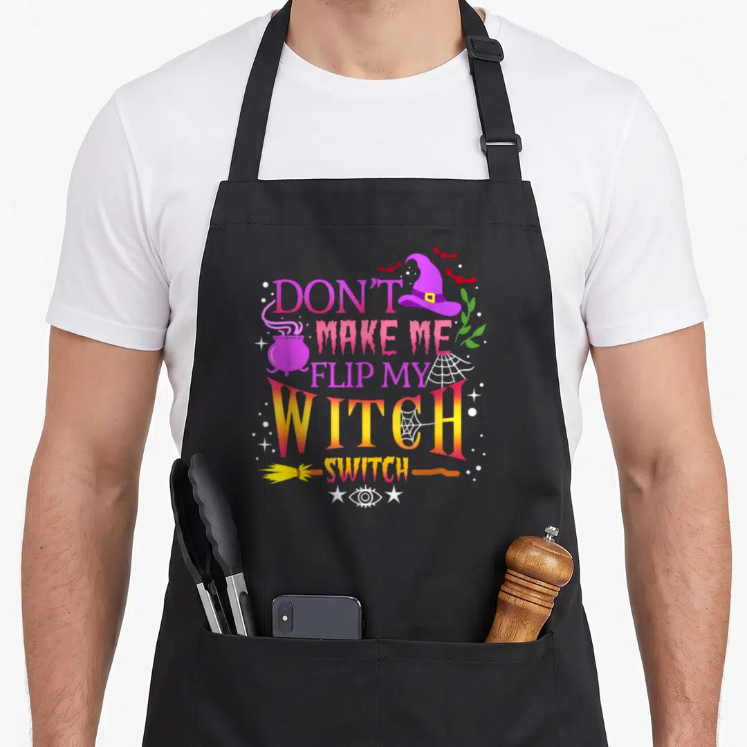 Flip halloween witch apron - Stacked text Don't Make Me Flip My Witch Switch with purple hat, cauldron, broom — shown on a black cotton canvas apron against a white background