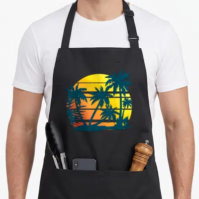 Coconut tree apron - Dark teal palm tree silhouettes against a striped yellow and orange gradient sun in a retro style — shown on a black cotton canvas apron against a white background