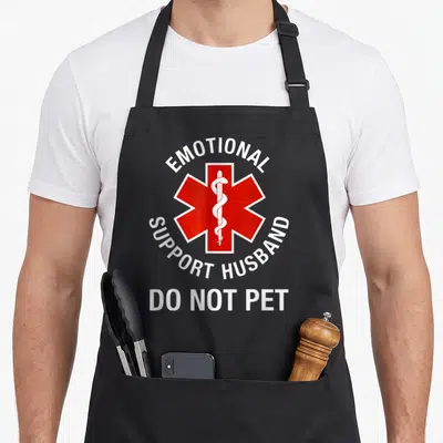 Cute pet husband apron - Red Star of Life with Emotional Support Husband Do Not Pet white text — shown on a black cotton canvas apron against a white background