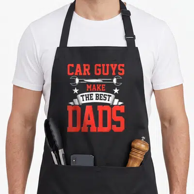 Funny car garage apron - Red and white text reading Car Guys Make The Best Dads with a wrench and two stars — shown on a black cotton canvas apron against a white background