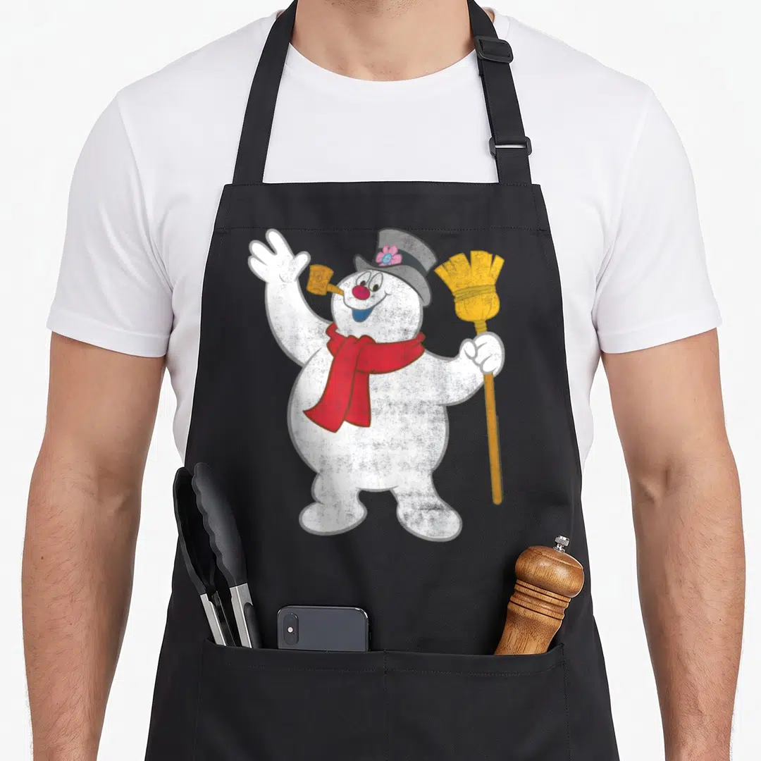 Portrait snowman apron - Cartoon snowman with red scarf, grey hat, yellow broom, and pipe in mouth — shown on a black cotton canvas apron against a white background