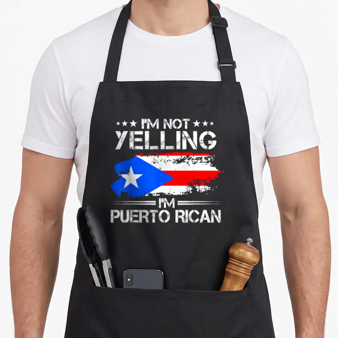 Yelling puerto pride apron - Distressed Puerto Rican flag with white text I'm Not Yelling I'm Puerto Rican — shown on a black cotton canvas apron against a white background