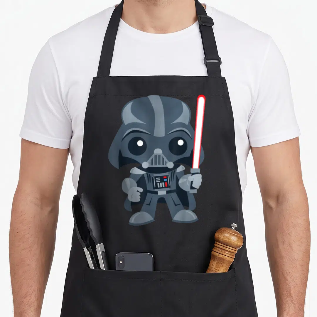 Saber cartoon apron - Cartoon Darth Vader holding red lightsaber in grey white and red — shown on a black cotton canvas apron against a white background