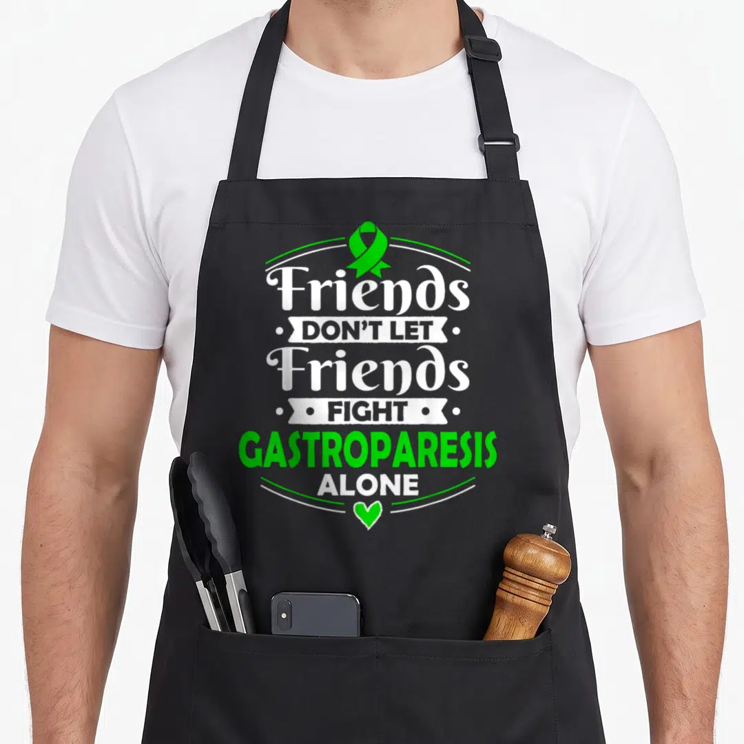 Stomach gastroparesis awareness apron - Green ribbon and heart with stacked white and green text reading Friends Don't — shown on a black cotton canvas apron against a white background