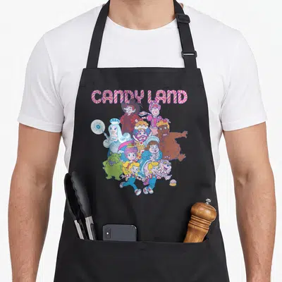 Land cotton candy apron - CANDY LAND text arching over a group of cartoon characters and a small cupcake in pastel — shown on a black cotton canvas apron against a white background