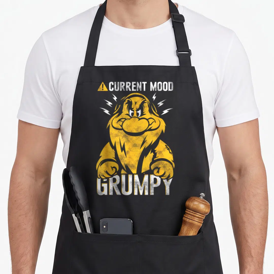 Mood snow white apron - Yellow grumpy dwarf with lightning bolts and CURRENT MOOD GRUMPY text in distressed white font — shown on a black cotton canvas apron against a white background