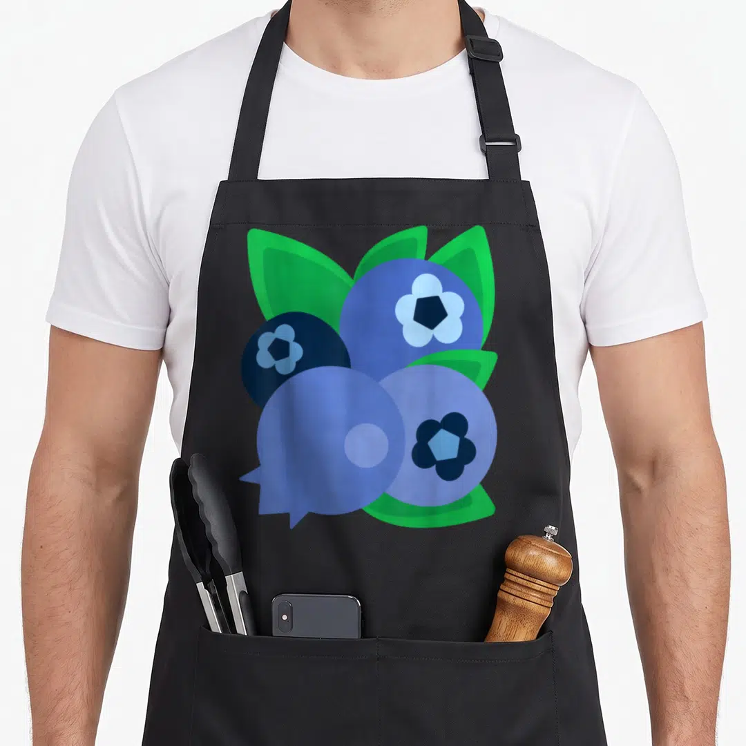 Blueberry halloween apron - Three cartoon blueberries and green leaves printed on black fabric — shown on a black cotton canvas apron against a white background