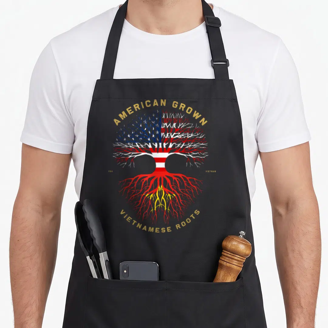 Vietnamese american flag apron - Tree with USA flag canopy and red roots. American Grown Vietnamese Roots text. Gold — shown on a black cotton canvas apron against a white background