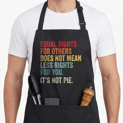Equality pie apron - Stacked red orange yellow blue teal beige text reading equal rights for others its not pie — shown on a black cotton canvas apron against a white background