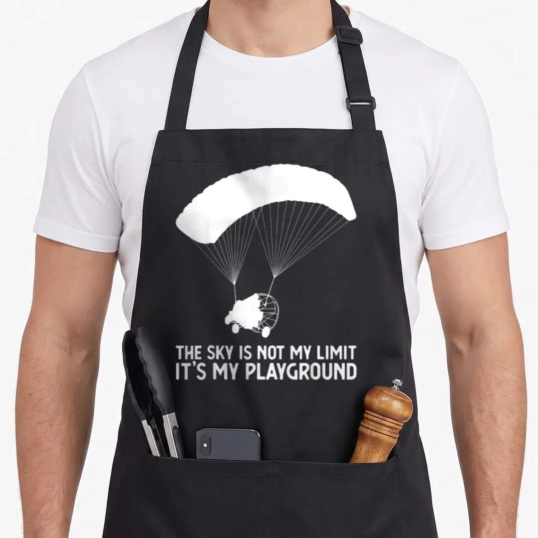 Ppc sky apron - White paramotor silhouette and text THE SKY IS NOT MY LIMIT IT'S MY PLAYGROUND — shown on a black cotton canvas apron against a white background