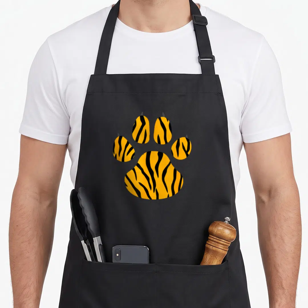 Tiger paw print apron - Orange and black tiger striped paw print graphic on canvas apron — shown on a black cotton canvas apron against a white background