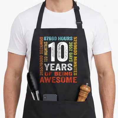 10th month birthday apron - White 10 surrounded by colored time stats and Years of Being Awesome text — shown on a black cotton canvas apron against a white background