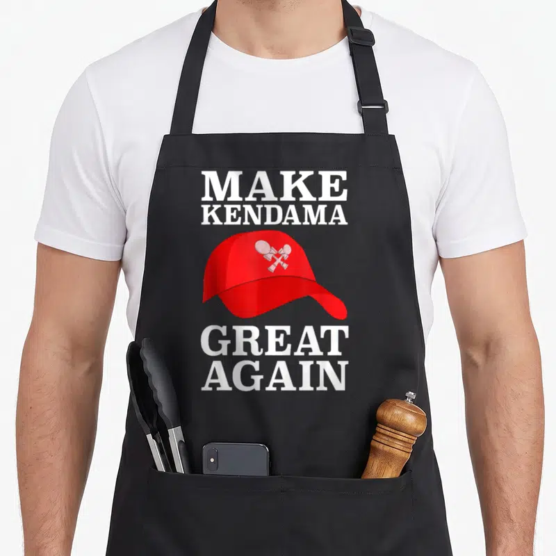 Kendama fan gear apron - Red baseball cap with two crossed kendamas and white slogan text — shown on a black cotton canvas apron against a white background