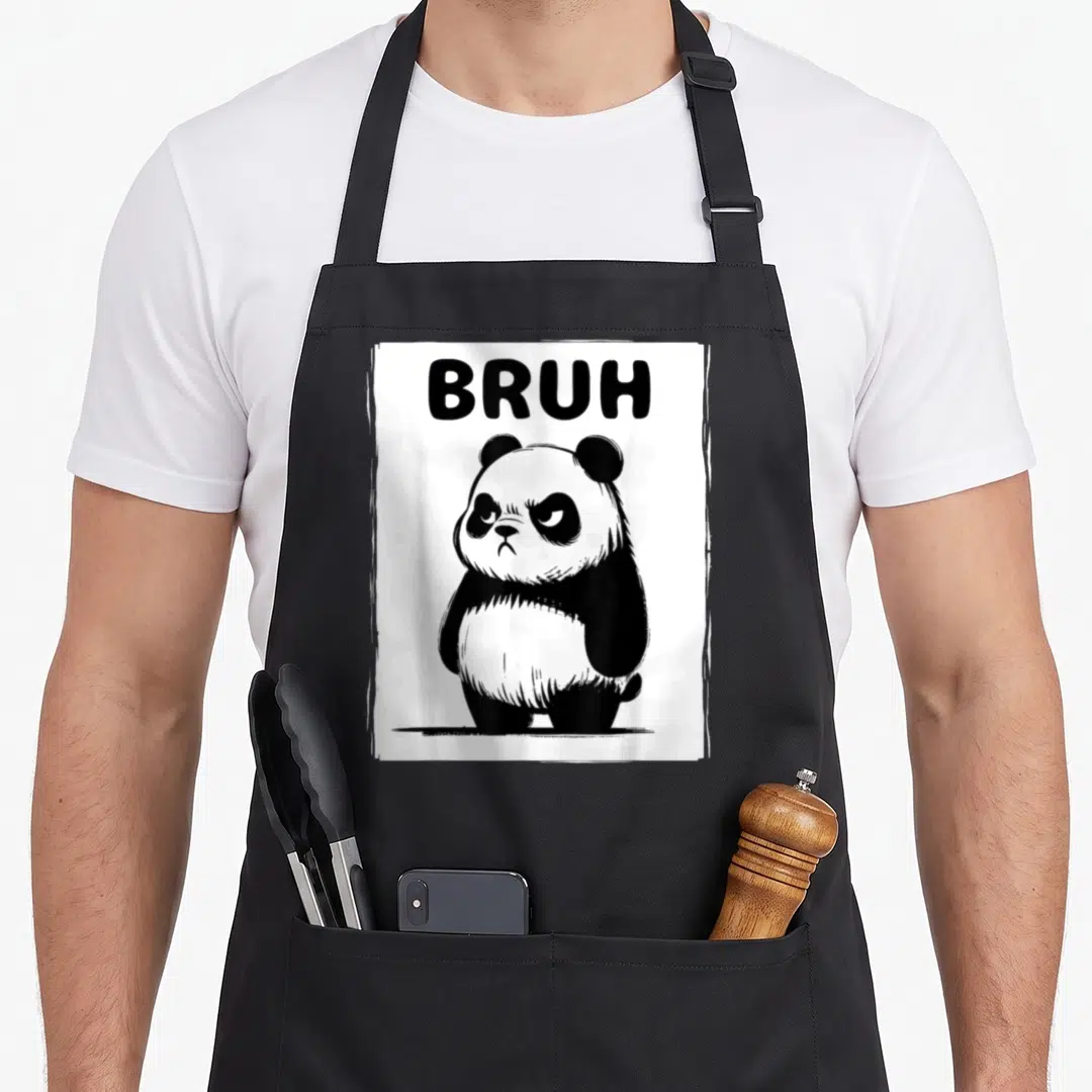 Bruh panda apron - Cartoon panda with BRUH text in distressed white frame — shown on a black cotton canvas apron against a white background