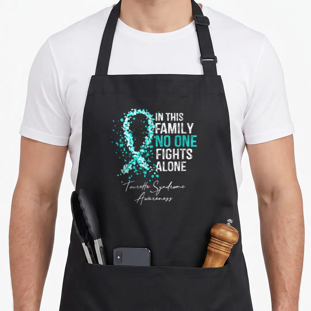 Tourette family aprons - Cyan heart ribbon and text IN THIS FAMILY NO ONE FIGHTS ALONE with Tourette Syndrome Awareness — shown on a black cotton canvas apron against a white background