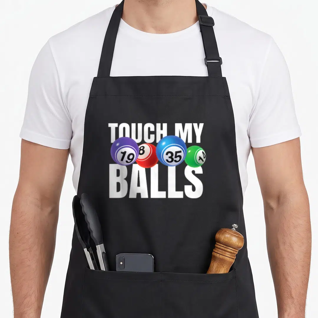 Touch bingo aprons - TOUCH MY BALLS text with four numbered bingo balls in purple red blue green — shown on a black cotton canvas apron against a white background