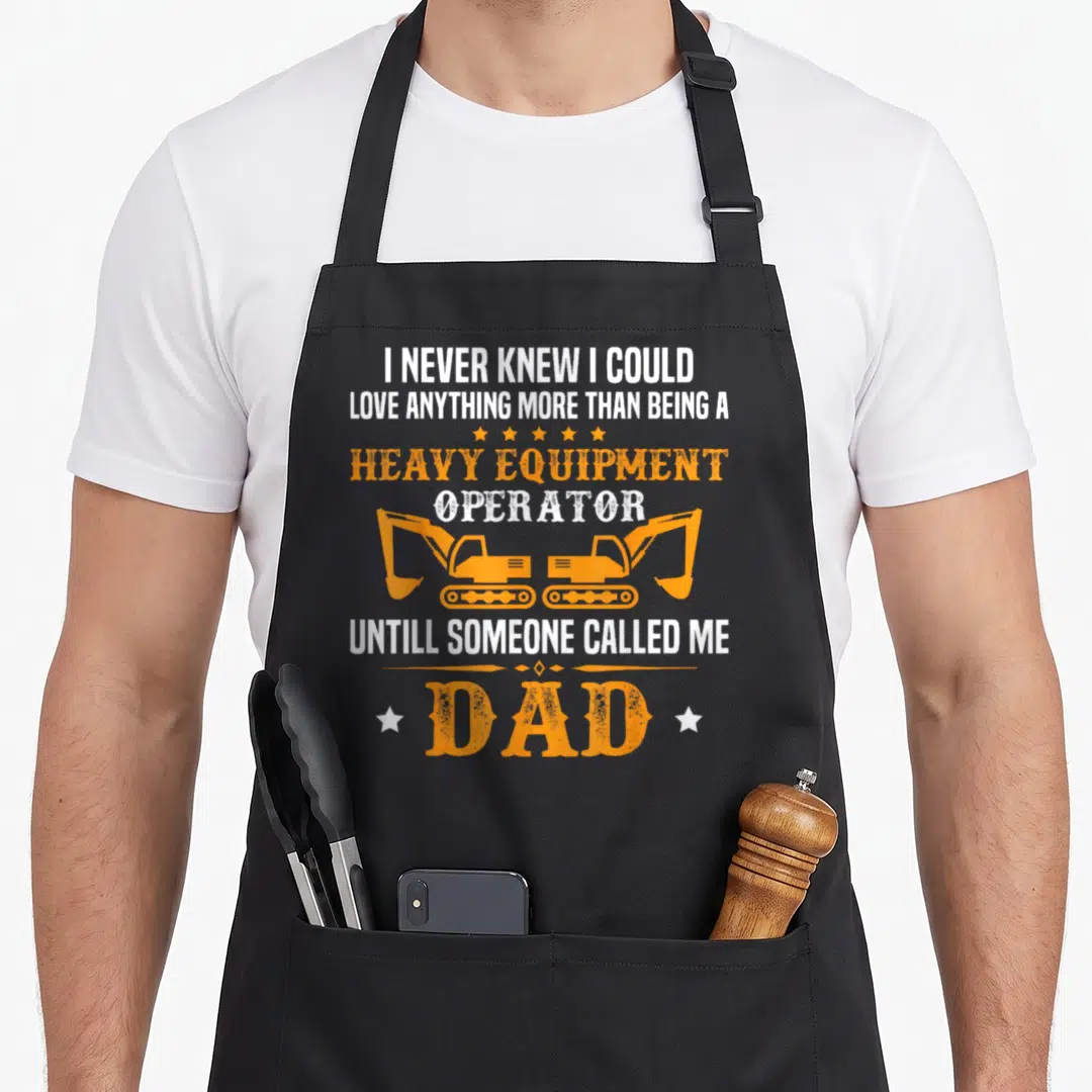 Bulldozer heavy canvas aprons - Orange excavators and white text reading Heavy Equipment Operator Dad with distressed — shown on a black cotton canvas apron against a white background
