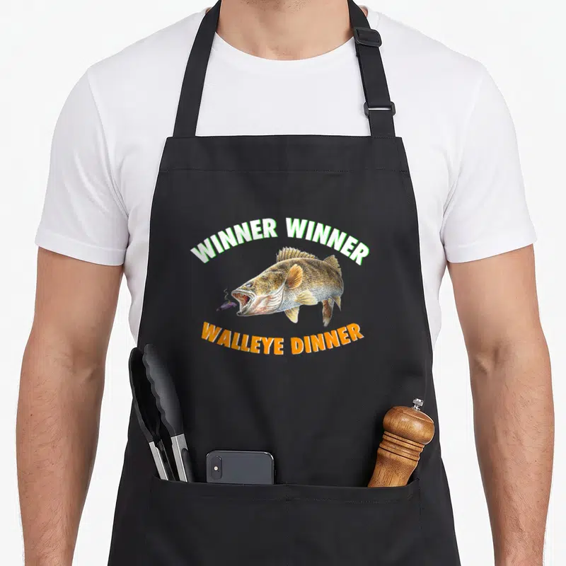 Funny fish fry apron - Realistic walleye with lure and arched text Winner Winner Walleye Dinner in green orange gold — shown on a black cotton canvas apron against a white background