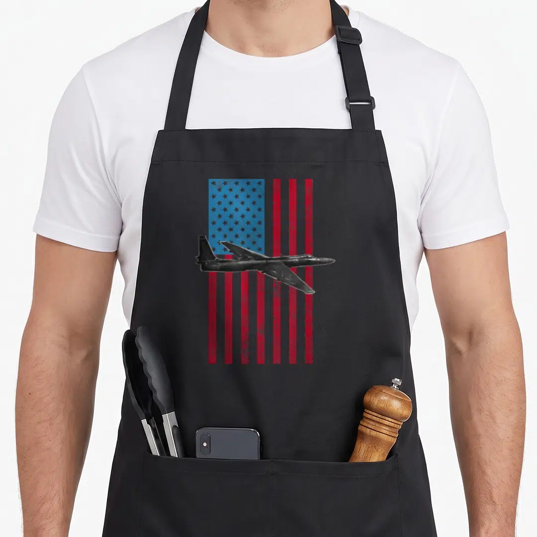 Dragon american flag apron - Black jet flying over distressed red white and blue stars and stripes flag — shown on a black cotton canvas apron against a white background