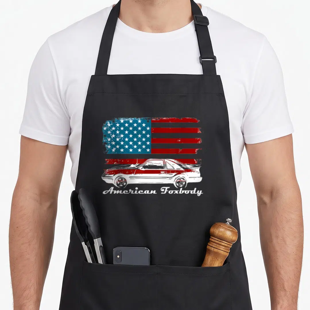 Foxbody american flag apron - Distressed red white blue flag with white car silhouette and American Foxbody script — shown on a black cotton canvas apron against a white background