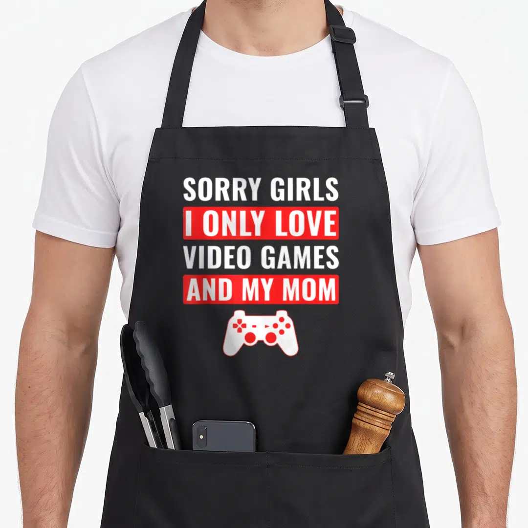 Game valentine's day apron - Sorry Girls I Only Love Video Games And My Mom text with red bars and white controller — shown on a black cotton canvas apron against a white background