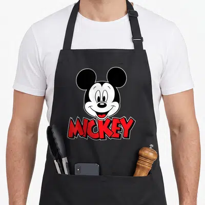 Retro crazy mouse man apron - Mickey Mouse head above red MICKEY text in black and white cartoon style — shown on a black cotton canvas apron against a white background
