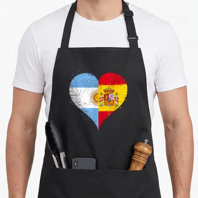 Argentina spanish aprons - Distressed heart split vertically with Argentinian blue white stripes and Spanish red yellow — shown on a black cotton canvas apron against a white background