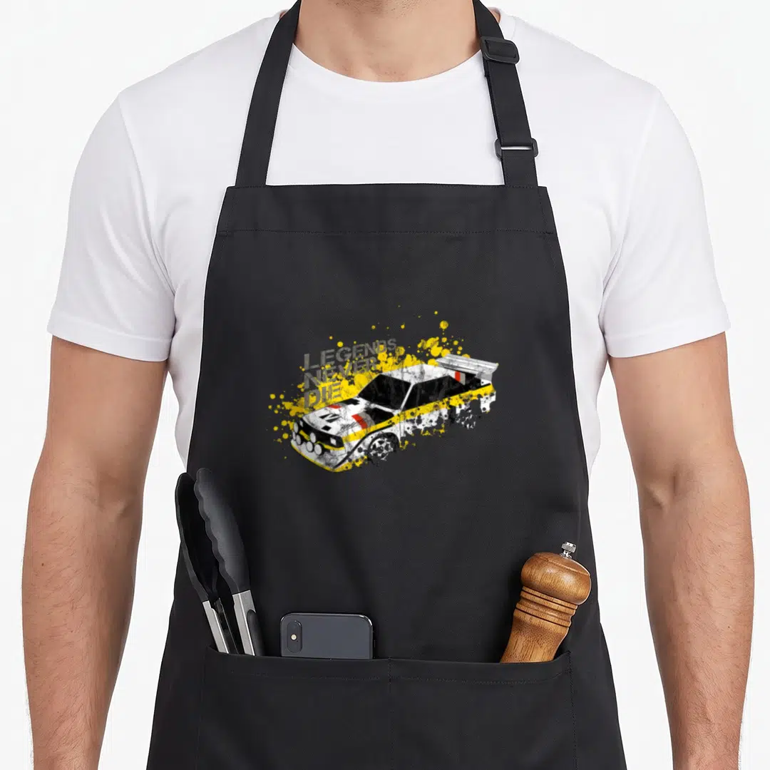 German car apron - Distressed white yellow black rally car with legends never die text and splatters — shown on a black cotton canvas apron against a white background