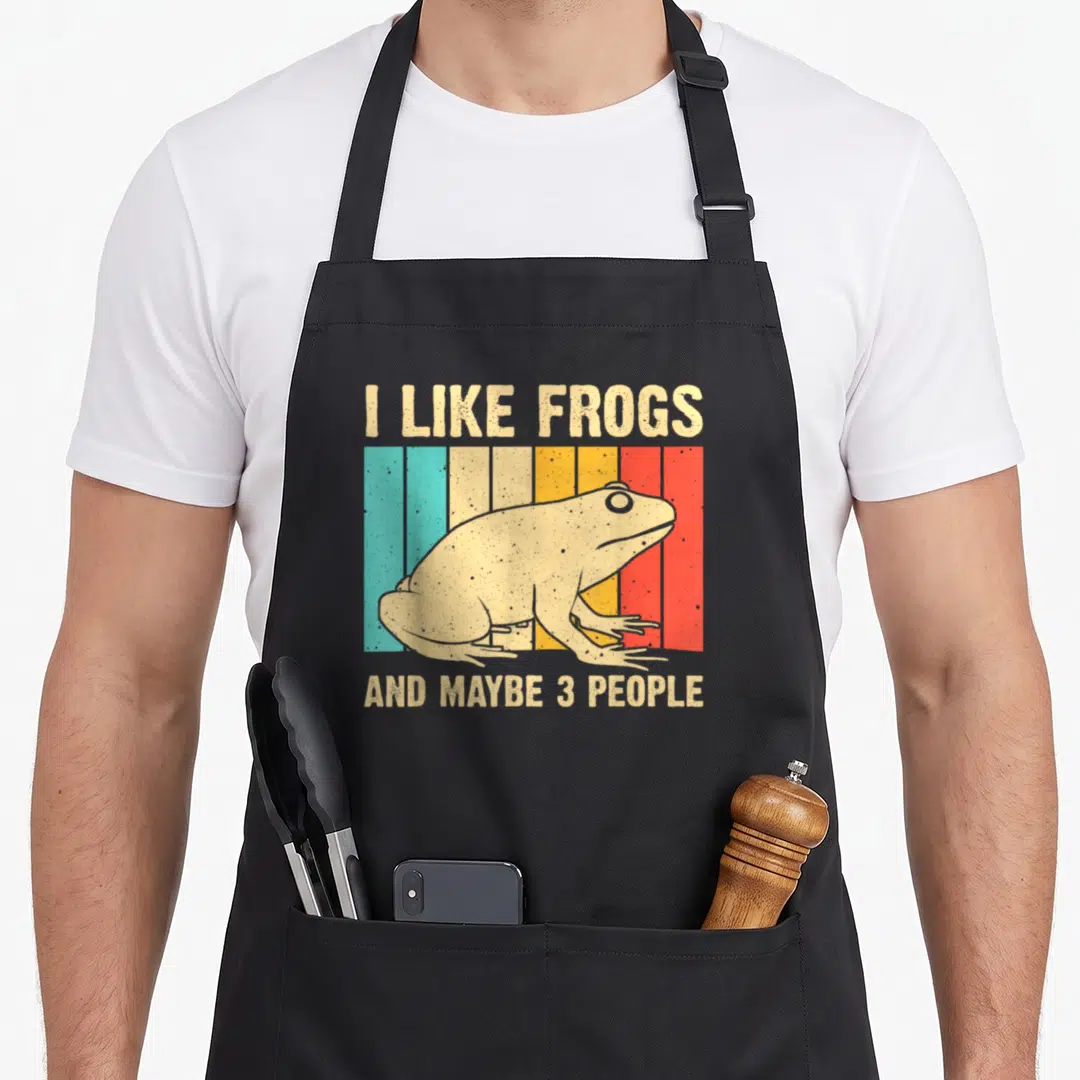 Toad amphibian frog aprons - Retro beige frog on teal yellow orange red stripes with text about liking frogs and few — shown on a black cotton canvas apron against a white background