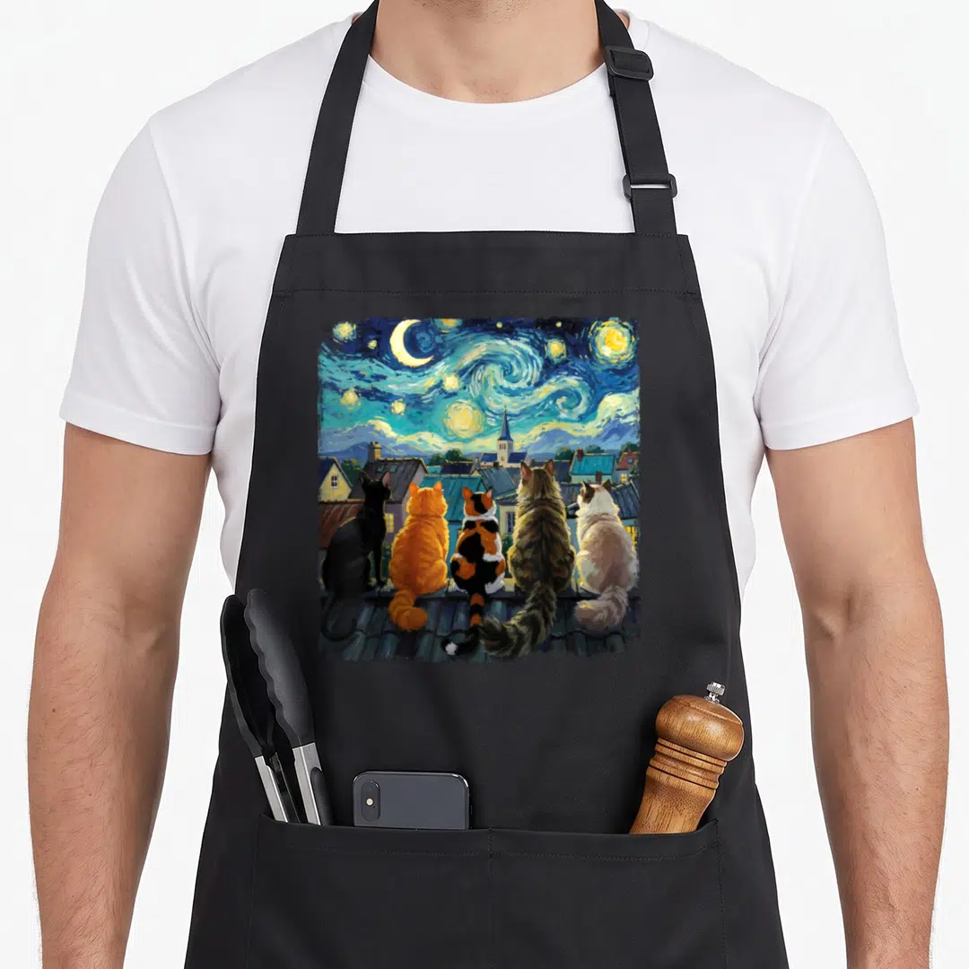 Rooftop van gogh apron - Five cats sitting on a rooftop watching a swirling starry night sky with a crescent moon — shown on a black cotton canvas apron against a white background