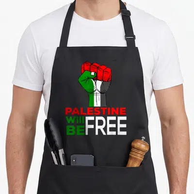 Flag palestine apron - Raised fist in red green white black above stacked text PALESTINE Will BE FREE — shown on a black cotton canvas apron against a white background