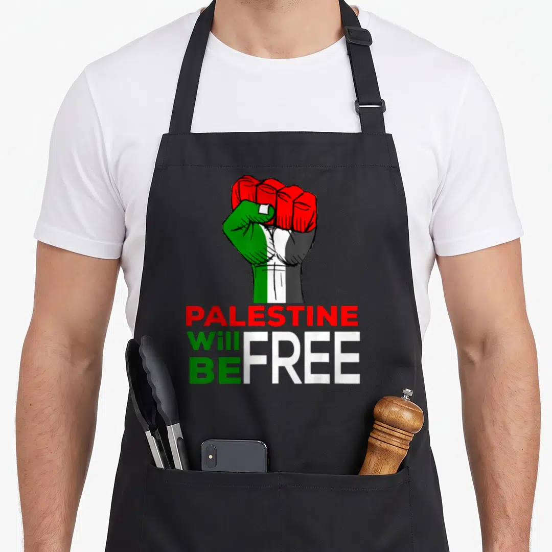 Flag palestine apron - Raised fist in red green white black above stacked text PALESTINE Will BE FREE — shown on a black cotton canvas apron against a white background