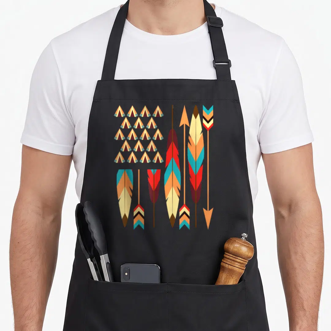 Pride native american apron - Grid of tipis and vertical feathers in red, blue, orange, cream, and brown — shown on a black cotton canvas apron against a white background