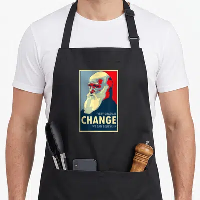 Gradual change apron - Retro Darwin portrait with Very Gradual Change We Can Believe In text — shown on a black cotton canvas apron against a white background