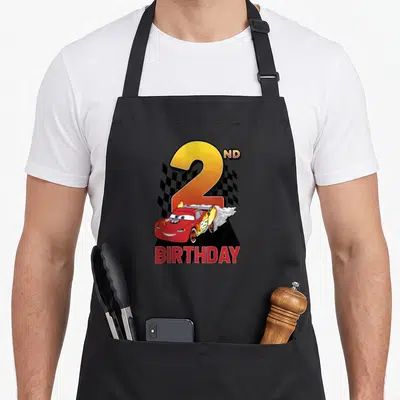 Youth 2nd apron - Red race car with fire in front of yellow number 2 and checkered flag — shown on a black cotton canvas apron against a white background