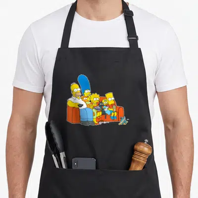 Homer couch apron - Family sitting on orange couch with yellow skin, blue hair, and trash on floor — shown on a black cotton canvas apron against a white background