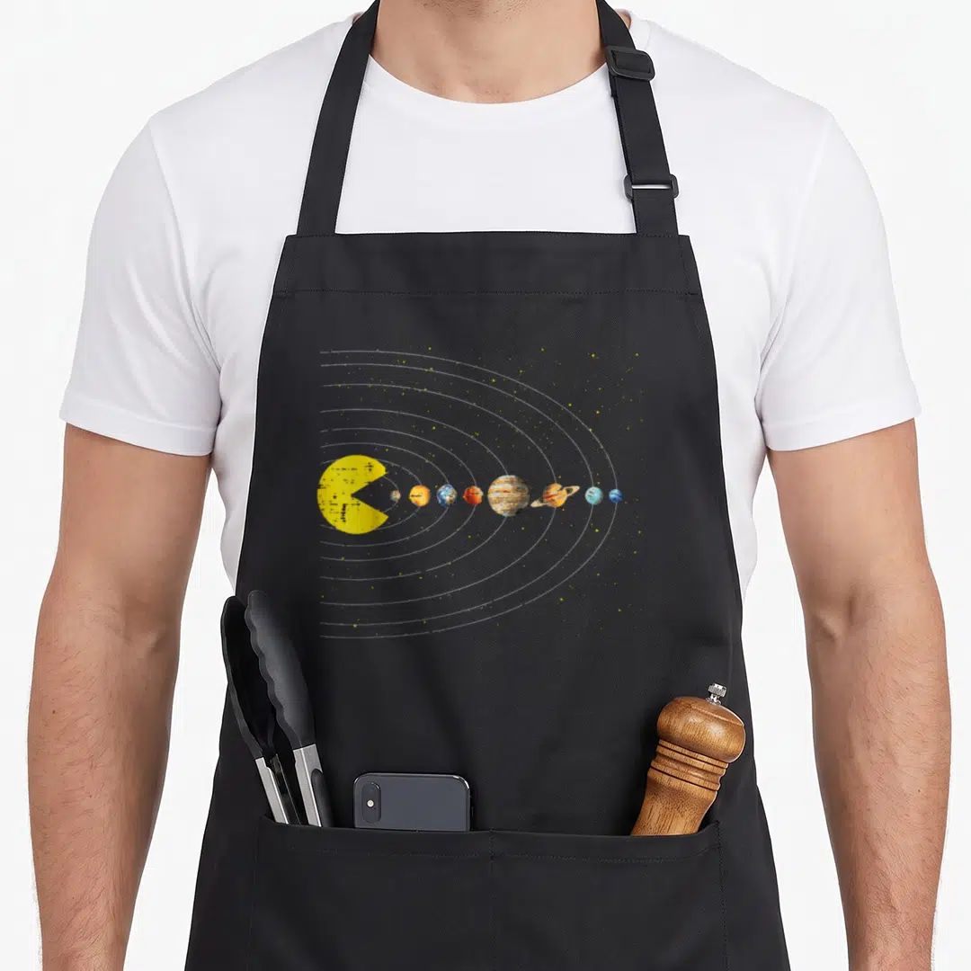 Eating game aprons - Yellow sun eating planets in white orbit lines with scattered yellow stars — shown on a black cotton canvas apron against a white background