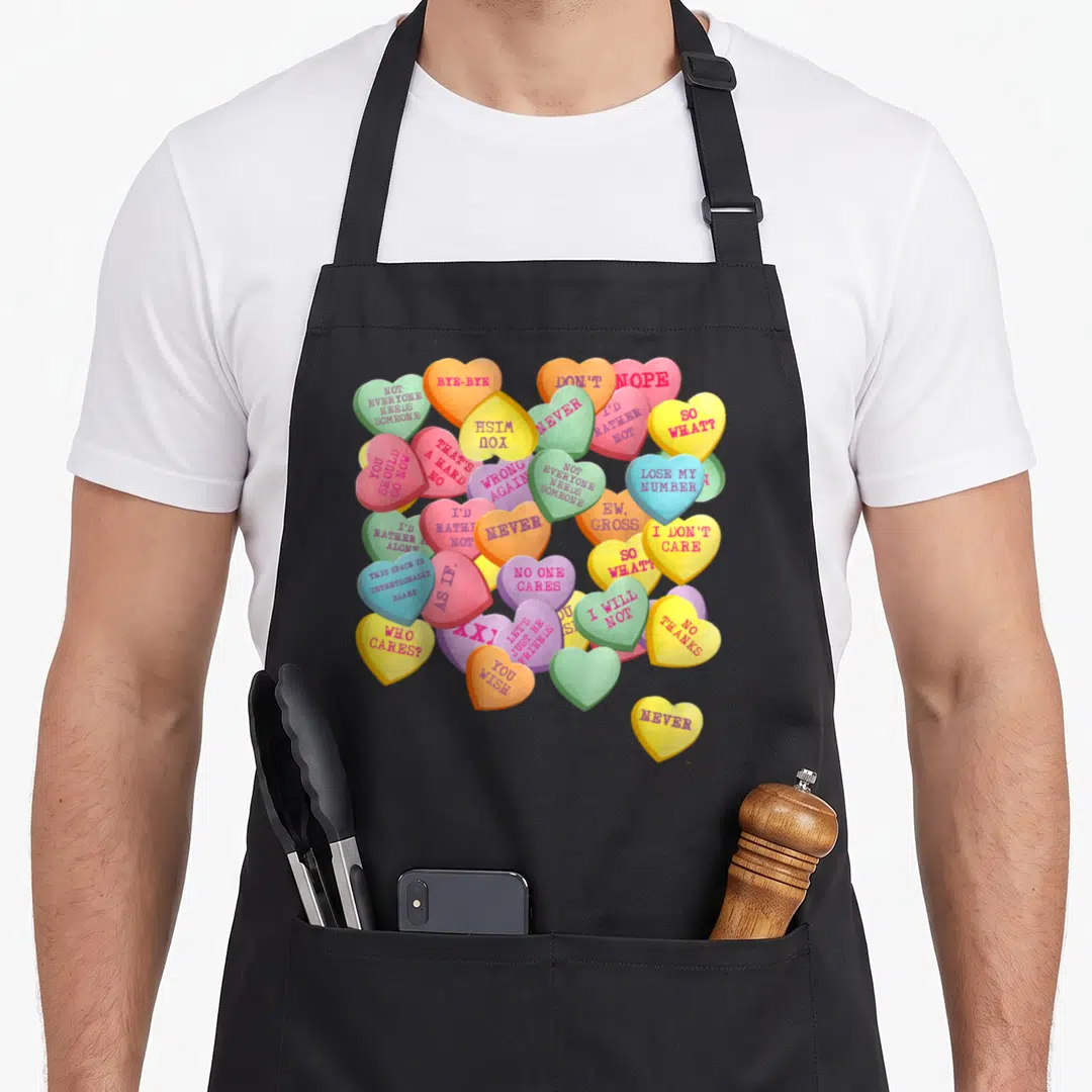 Conversation cotton candy apron - Multicolored candy hearts with rejection text like 'Nope', 'Never', and 'I'd Rather — shown on a black cotton canvas apron against a white background