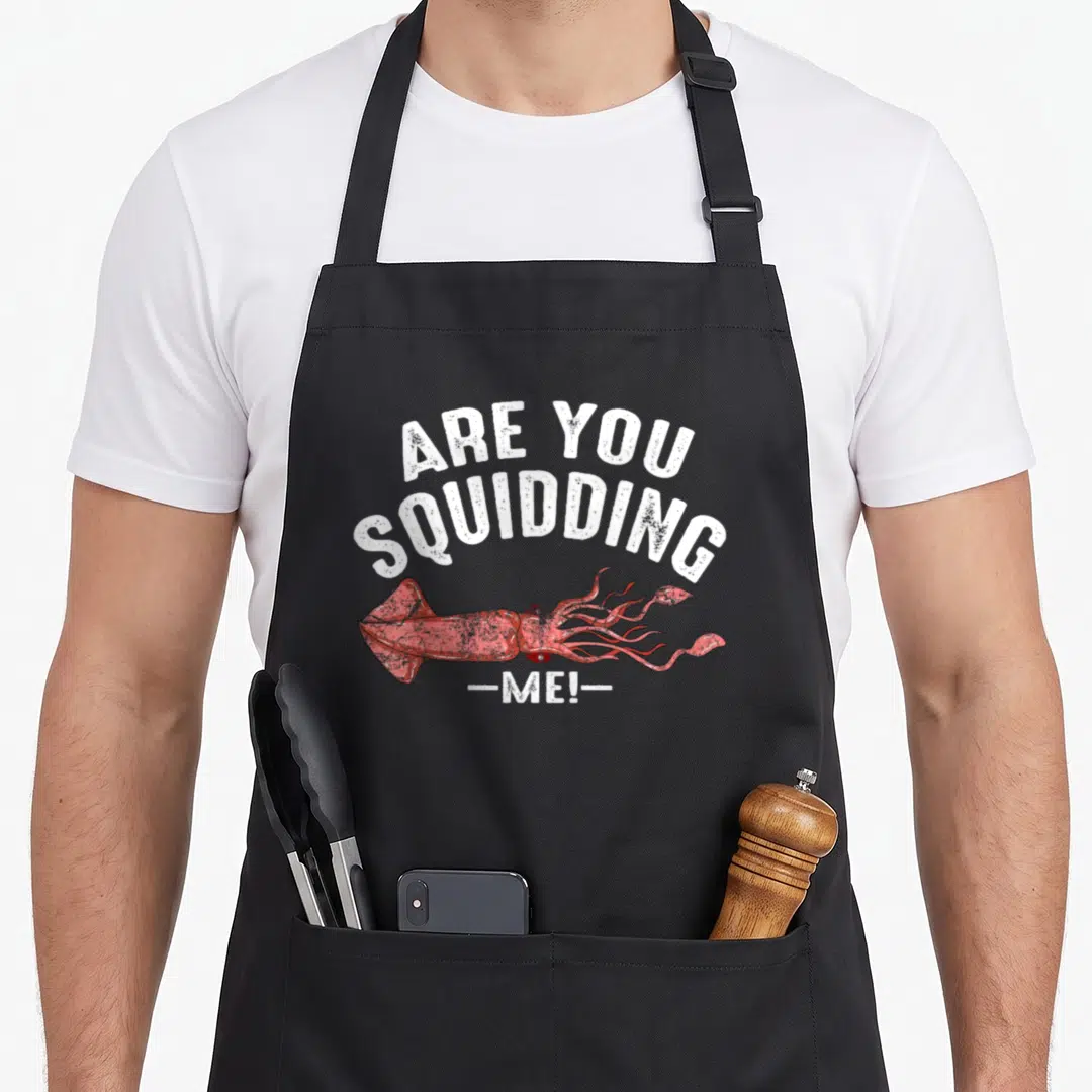 Squidding fish apron - Red squid illustration with arched white text reading are you squidding me in distressed font — shown on a black cotton canvas apron against a white background
