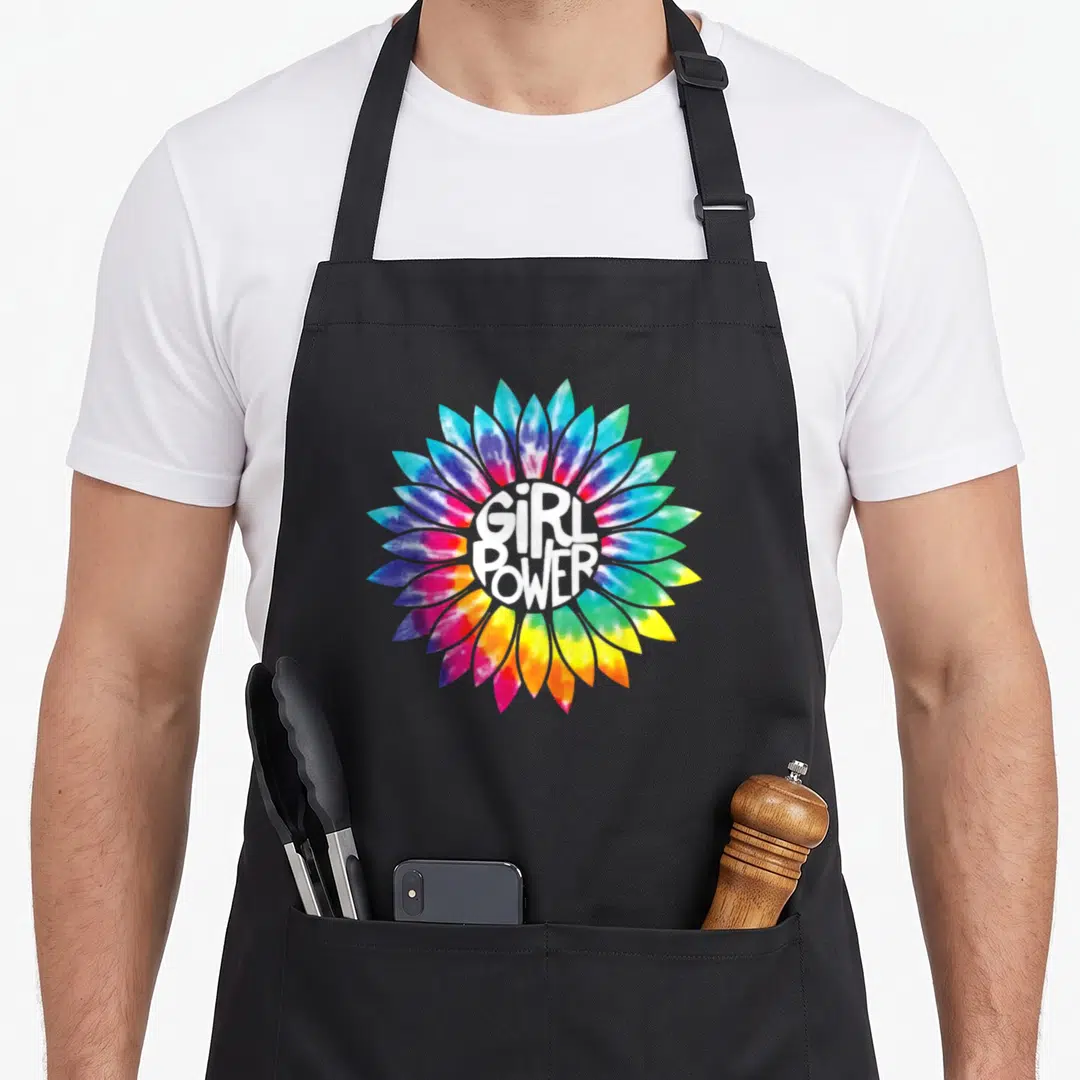 Power hippie apron - Multicolored tie-dye flower with white GIRL POWER text centered on front panel — shown on a black cotton canvas apron against a white background