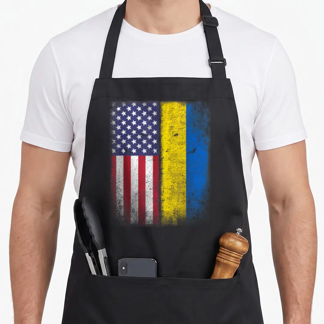 Cute ukrainian american flag apron - Distressed USA and Ukraine flags side by side in blue white red and yellow — shown on a black cotton canvas apron against a white background