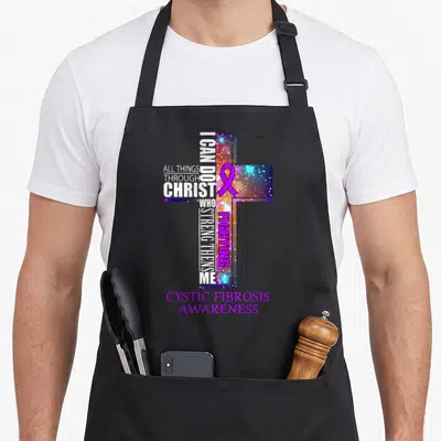 Cystic christmas apron - Galaxy cross with purple ribbon and fighting cystic fibrosis awareness text — shown on a black cotton canvas apron against a white background