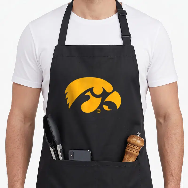 Icon iowa hawkeyes apron - Minimalist yellow hawk head graphic centered on grey background — shown on a black cotton canvas apron against a white background
