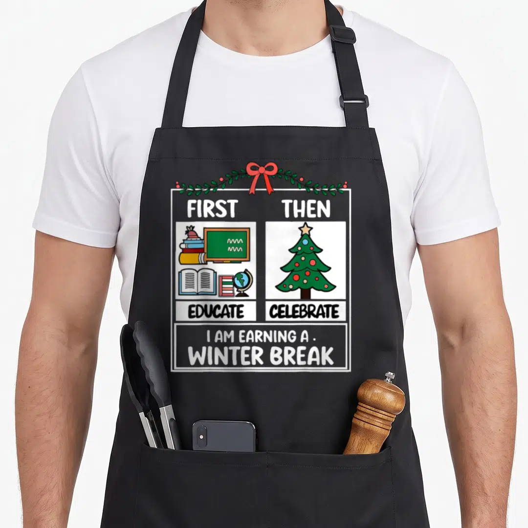 Educate christmas aprons - Cartoon books chalkboard and Christmas tree with First Educate Then Celebrate text — shown on a black cotton canvas apron against a white background
