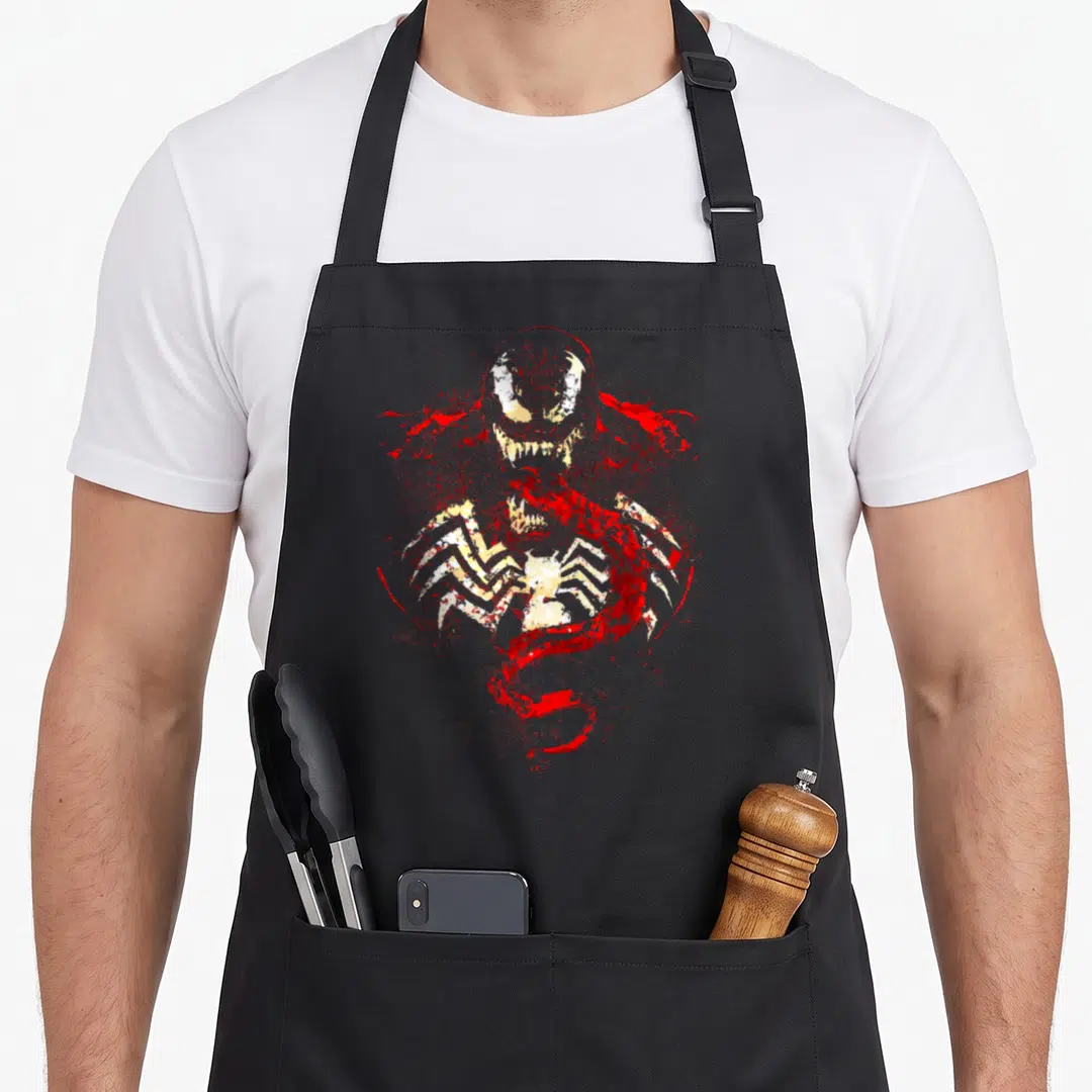 Splatter novelty apron - Red and white distressed Carnage head and torso with white spider symbol on chest — shown on a black cotton canvas apron against a white background