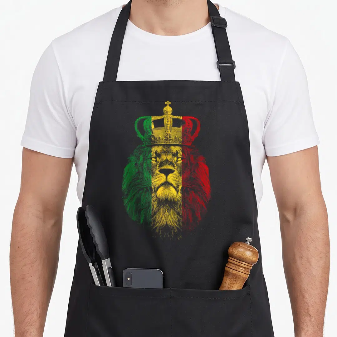 Rasta lion apron - Line-art lion head with crown filled with vertical green, yellow, and red bands — shown on a black cotton canvas apron against a white background