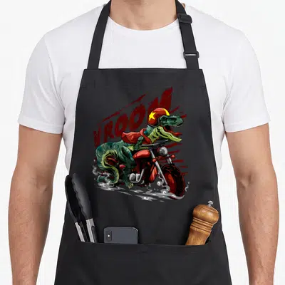 Motorcycle dinosaur apron - Tyrannosaurus Rex riding red motorcycle wearing helmet with VROOM text in red and green — shown on a black cotton canvas apron against a white background