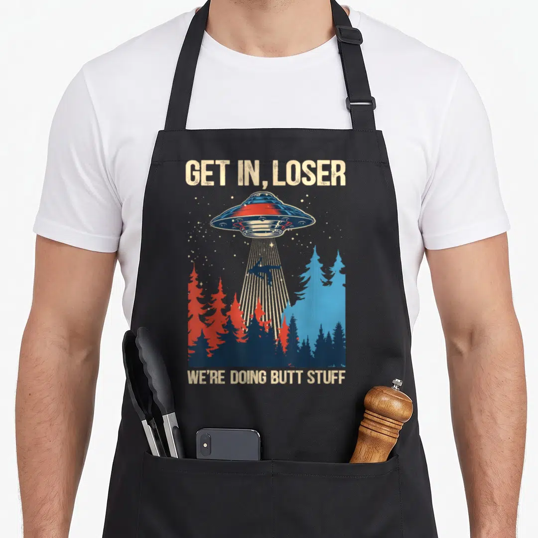 Abduction butt funny apron - Retro UFO beaming person from red and blue trees with text GET IN LOSER — shown on a black cotton canvas apron against a white background