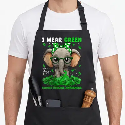 Kidney bandana apron - Cartoon elephant with green glasses and polka dot headband holding ribbon among green flowers — shown on a black cotton canvas apron against a white background