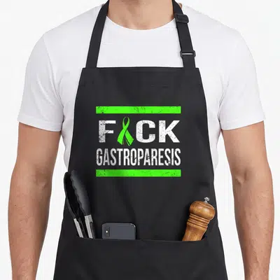Support gastroparesis awareness apron - Green ribbon replaces U in FICK text between two green bars — shown on a black cotton canvas apron against a white background